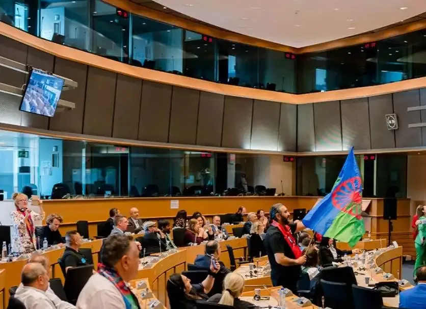 People in conference room with a blue-green flag.